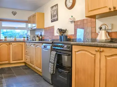 a kitchen with wooden cabinets and a stove top oven at Catbells in Arlecdon