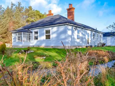 a white house with a chimney on top of a yard at Clarksburn Blue in Monreith
