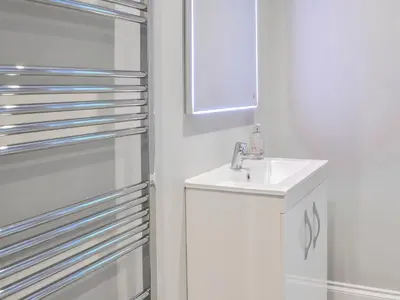 a white bathroom with a sink and a mirror at Clarksburn Blue in Monreith