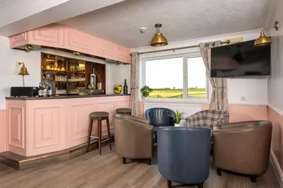 a bar with chairs and a television in a room at Big Pink House in Mealsgate