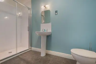 a bathroom with a shower and a sink and a toilet at Big Pink House in Mealsgate