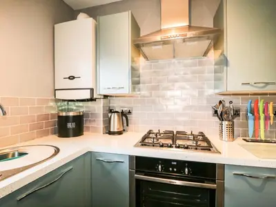 a kitchen with a stove top oven next to a sink at Fox's Retreat in Keswick