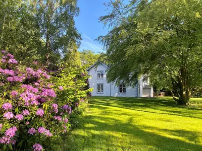 a white house with pink flowers in the yard at The Vicarage in Keswick