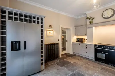 a kitchen with a refrigerator and a clock on the wall at The Vicarage in Keswick