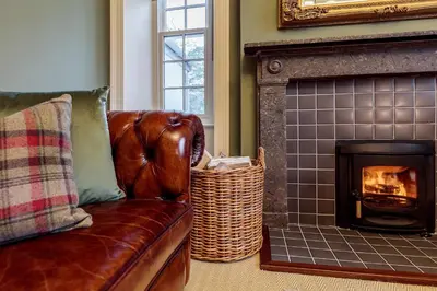 a leather couch in a living room with a fireplace at The Vicarage in Keswick