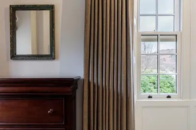 a window with a mirror and a curtain next to a dresser at The Vicarage in Keswick