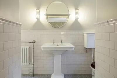 a white bathroom with a sink and a mirror at The Vicarage in Keswick