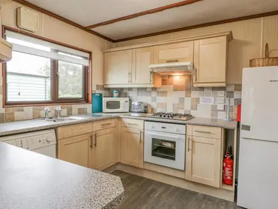 a kitchen with wooden cabinets and white appliances at Roe Deer Lodge in Newton Stewart