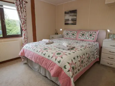 a bedroom with a pink bed and a window at Roe Deer Lodge in Newton Stewart