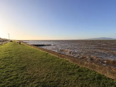 a grassy field next to a body of water at Solway View in Wigton