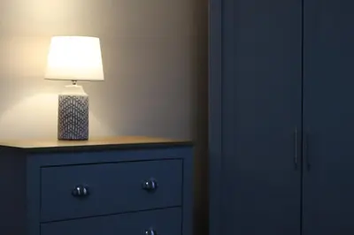 a lamp on top of a dresser in a bedroom at Troon Golf Apartment in Troon