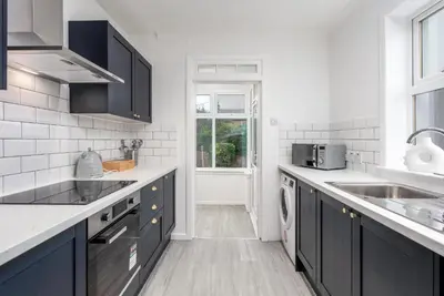 a kitchen with black cabinets and a sink at Wellington View - Donnini Apartments in Ayr