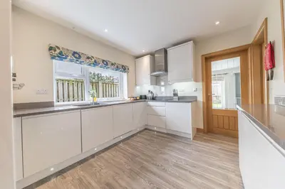 a kitchen with white cabinets and a window at Cherry Garth HOT TUB HIRE AVAILABLE in Keswick