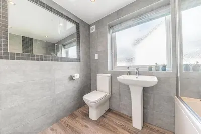 a bathroom with a toilet and a sink and a window at Cherry Garth HOT TUB HIRE AVAILABLE in Keswick