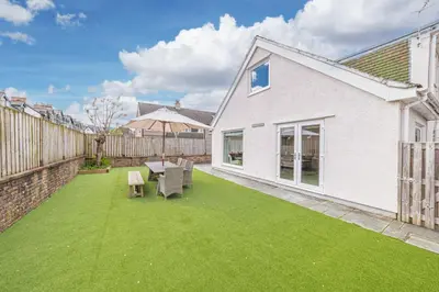 a garden with a table and chairs on a lawn at Cherry Garth HOT TUB HIRE AVAILABLE in Keswick