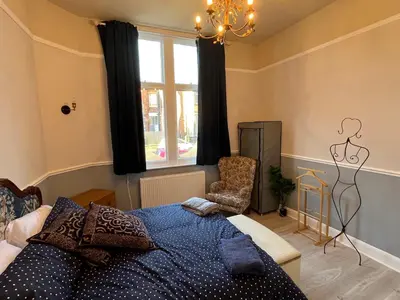 a bedroom with a bed and a window and a chair at Red Gables - Ground Floor in Carlisle