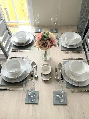 a dining room table with white plates and a vase of flowers at Cumbria Reach in Longtown