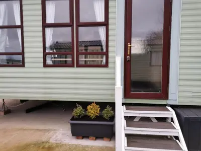 a house with a window and a potted plant at Holiday Caravan - Sleeps 4 with Parking in Whithorn