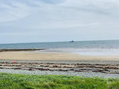 a sandy beach with a boat in the ocean at Holiday Caravan - Sleeps 4 with Parking in Whithorn