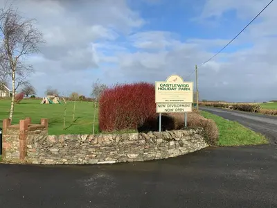 a sign on a stone wall next to a road at Holiday Caravan - Sleeps 4 with Parking in Whithorn
