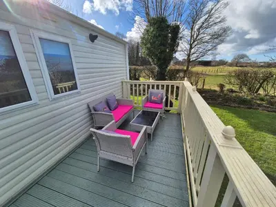 a deck with chairs and tables on a house at 24 The Beeches Caravan Park in Gilcrux