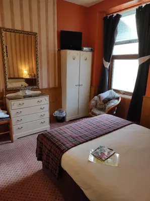a bedroom with a bed and a dresser and a mirror at All Seasons Guesthouse in Douglas