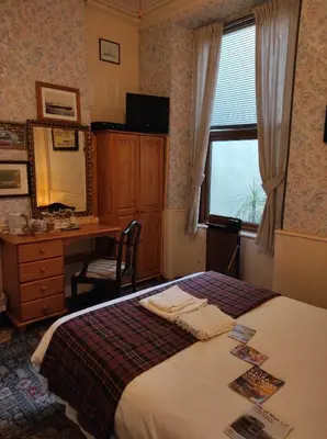 a bedroom with a bed and a desk and a window at All Seasons Guesthouse in Douglas