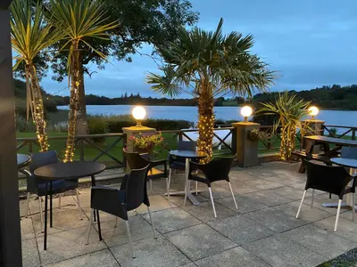 a patio with tables and chairs with a view of the water at The Inn on the Loch in Castle Douglas