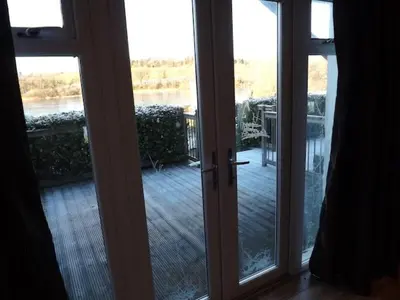 an open door to a balcony with a view of a deck at The Inn on the Loch in Castle Douglas