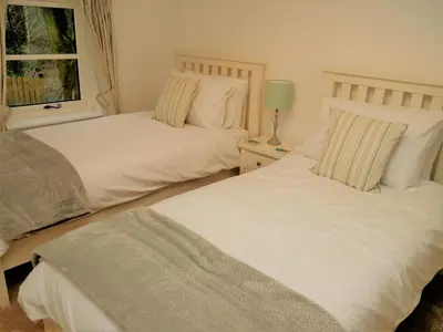 two white beds in a bedroom with a window at The Fish House in Kirkcudbright
