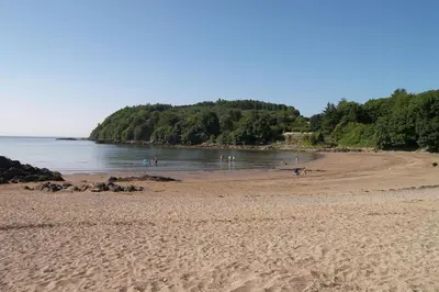 a sandy beach with people swimming in the water at The Fish House in Kirkcudbright