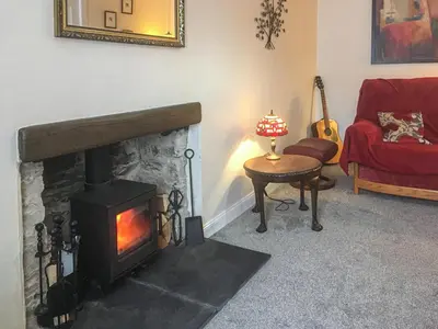 a living room with a fireplace and a red couch at Brae Cottage in Whithorn