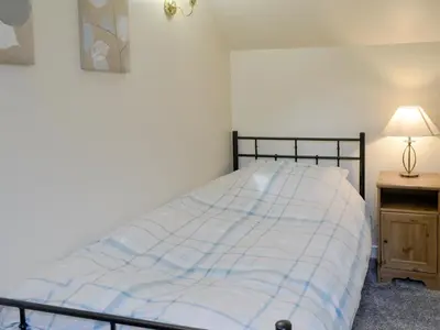 a bedroom with a bed and a lamp on a table at Brae Cottage in Whithorn