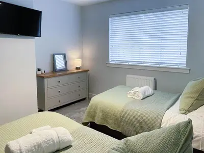 a bedroom with two beds and a dresser and a window at 2 Mote View- Uk37496 in Sandhead