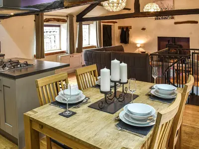 a dining room table with chairs and a kitchen at Forge Cottage in Keswick
