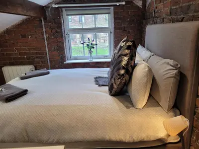 a large bed in a room with a brick wall at Carlisle Central, Cute Studio Appt, The Cupboard in Carlisle