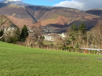a green field with a mountain in the background at Strawberry Fields in Cockermouth