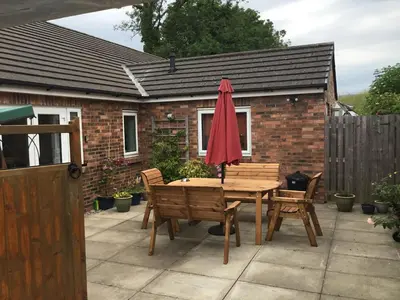 a table and chairs with a red umbrella on a patio at Strawberry Fields in Cockermouth