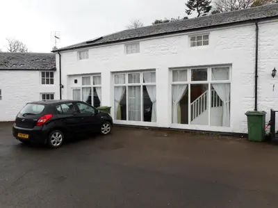 a black car parked in front of a white building at THE COACH HOUSE in Moffat
