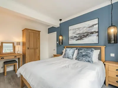 a bedroom with a bed with a blue wall at Brooksyde,Kippford in Kippford