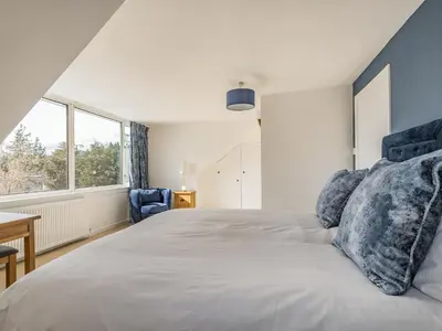 a bedroom with a large bed with blue pillows at Brooksyde,Kippford in Kippford