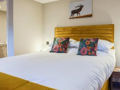 a bed with two pillows and a deer on the wall at Wallthwaite Cottage in Threlkeld