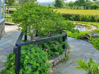 a garden with a black fence and flowers at Beacon Cottage in Ivegill