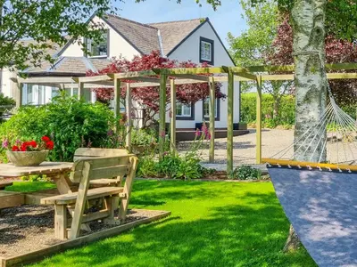 a garden with a hammock in front of a house at Beacon Cottage in Ivegill