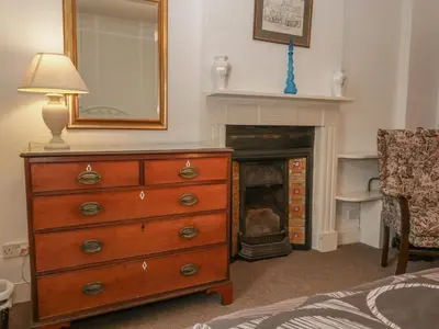 a bedroom with a dresser with a mirror and a fireplace at Beckside Farm in Millom