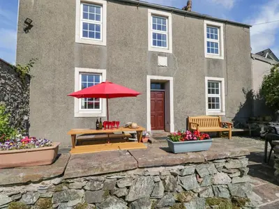 a house with a picnic table and an umbrella at Beckside Farm in Millom