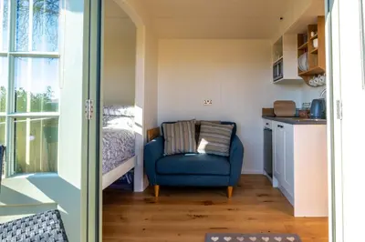 a room with a blue chair and a bed at Scalderskew Shepherds Hut in Gosforth