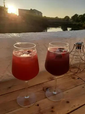 two wine glasses sitting on a wooden table with the sunset at Stunning Riverside Town House with views Ayrshire in Girvan