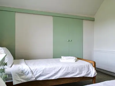 a bedroom with a bed with white sheets and green walls at Fell View in Lorton