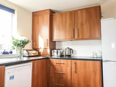a kitchen with wooden cabinets and a white refrigerator at Tilly Mint Cottage in Penrith